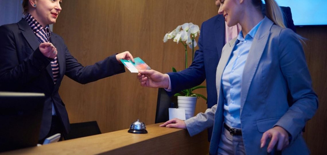 Hotel front desk agent handing a keycard to arriving guests during check-in