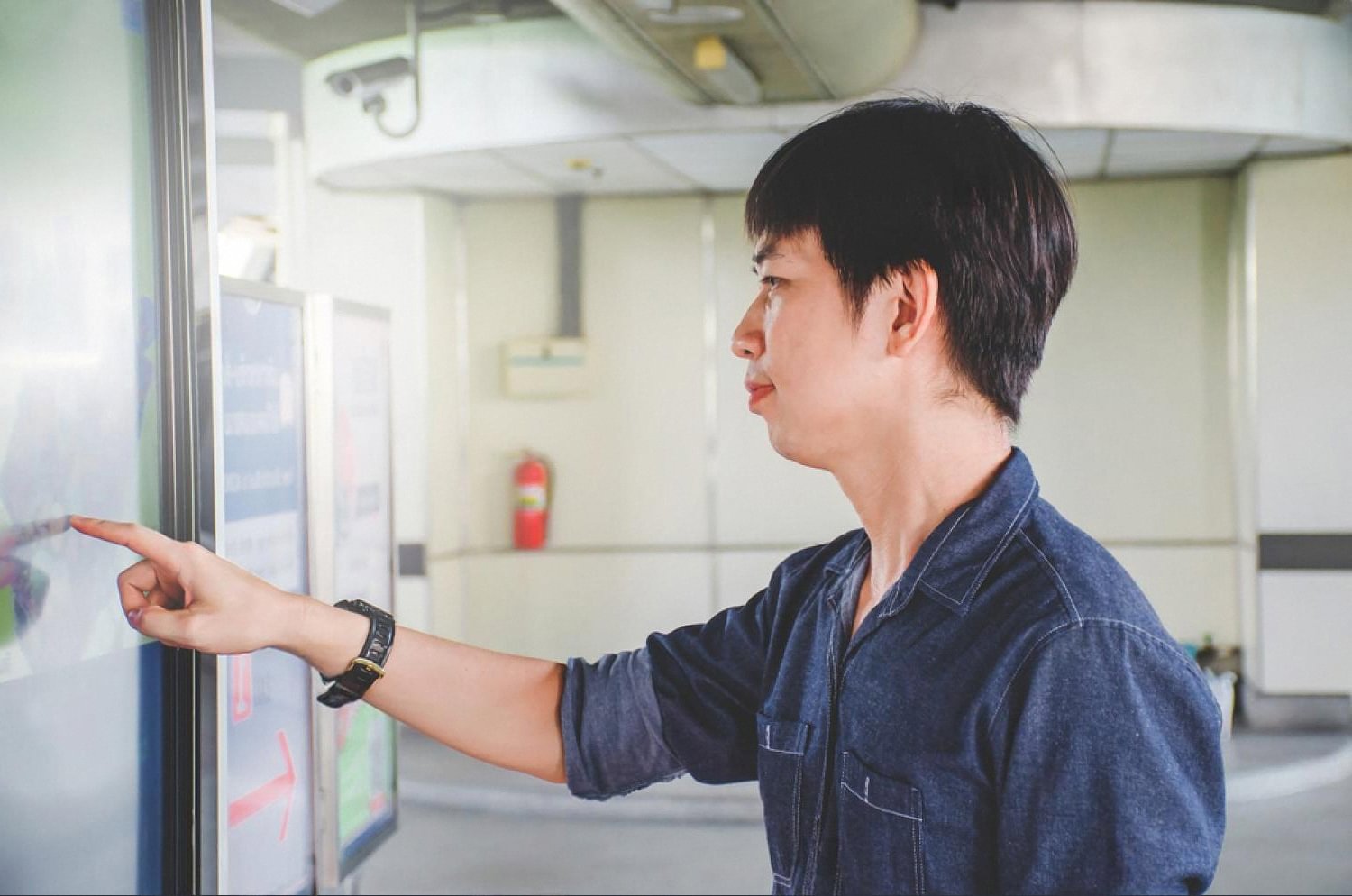 Guest tapping a self-service hospitality kiosk screen in a hotel lobby