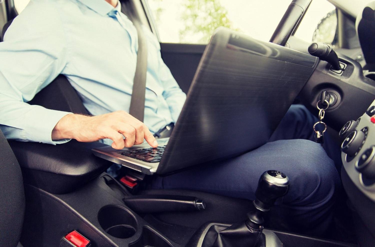Driver using a laptop inside a rental car to complete an online booking